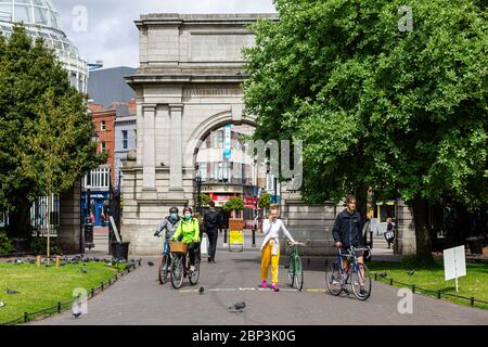 Personen mit Fahrrädern, die Gesichtsmasken tragen, betreten den St.Stephen`s Green Park in Dublin, der während der COVID-19-Pandemie die sozialen Distanzierungsregeln einhält. Stockfoto